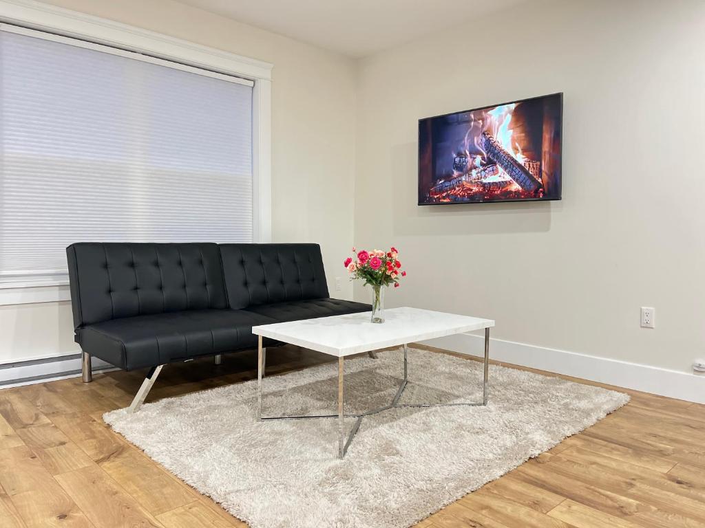 sala de estar con sofá negro y mesa en City Modern Apartment, en Charlottetown