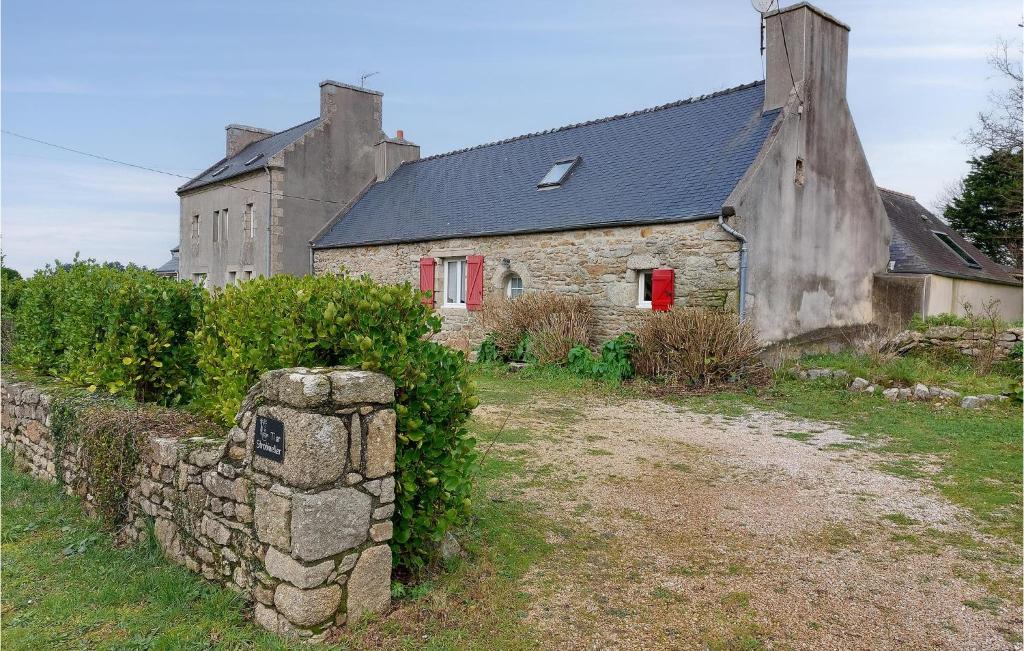 een oud stenen huis met rode ramen en een stenen muur bij Lovely Home In Plouguerneau With Wifi in Plouguerneau