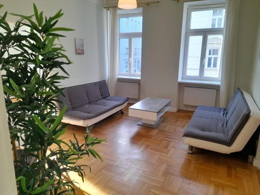 salon z 2 krzesłami, kanapą i rośliną w obiekcie Big Family Apartment w Wiedniu
