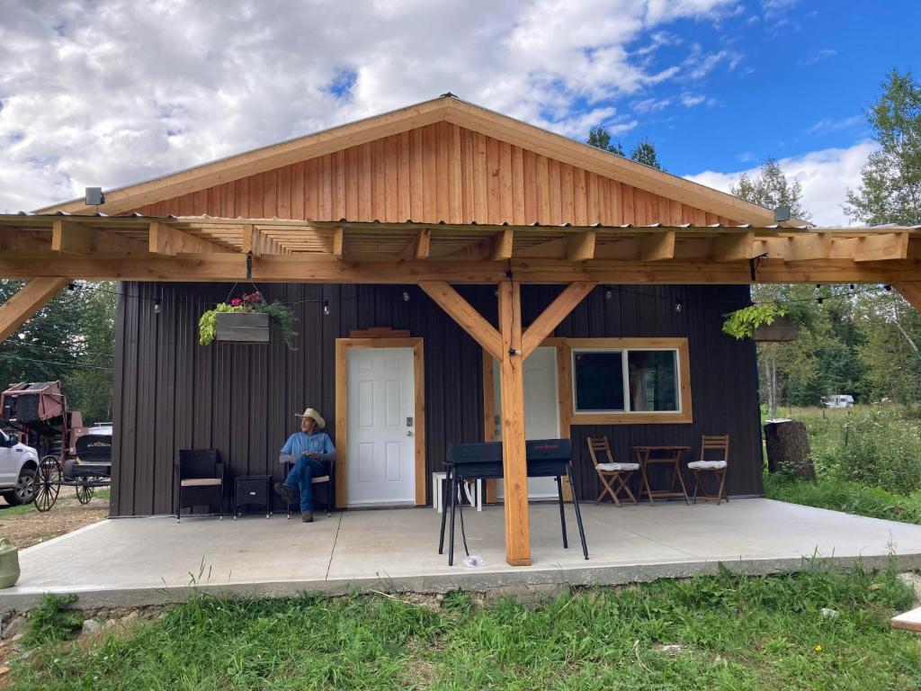 Una donna seduta sul portico di un capanno di Battle Creek Ranch, Wells Gray Park a Clearwater