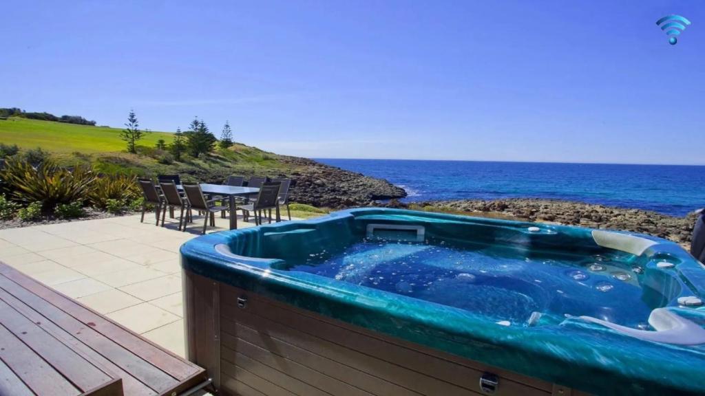 a hot tub on a deck next to the ocean at Aqua in Kiama Downs
