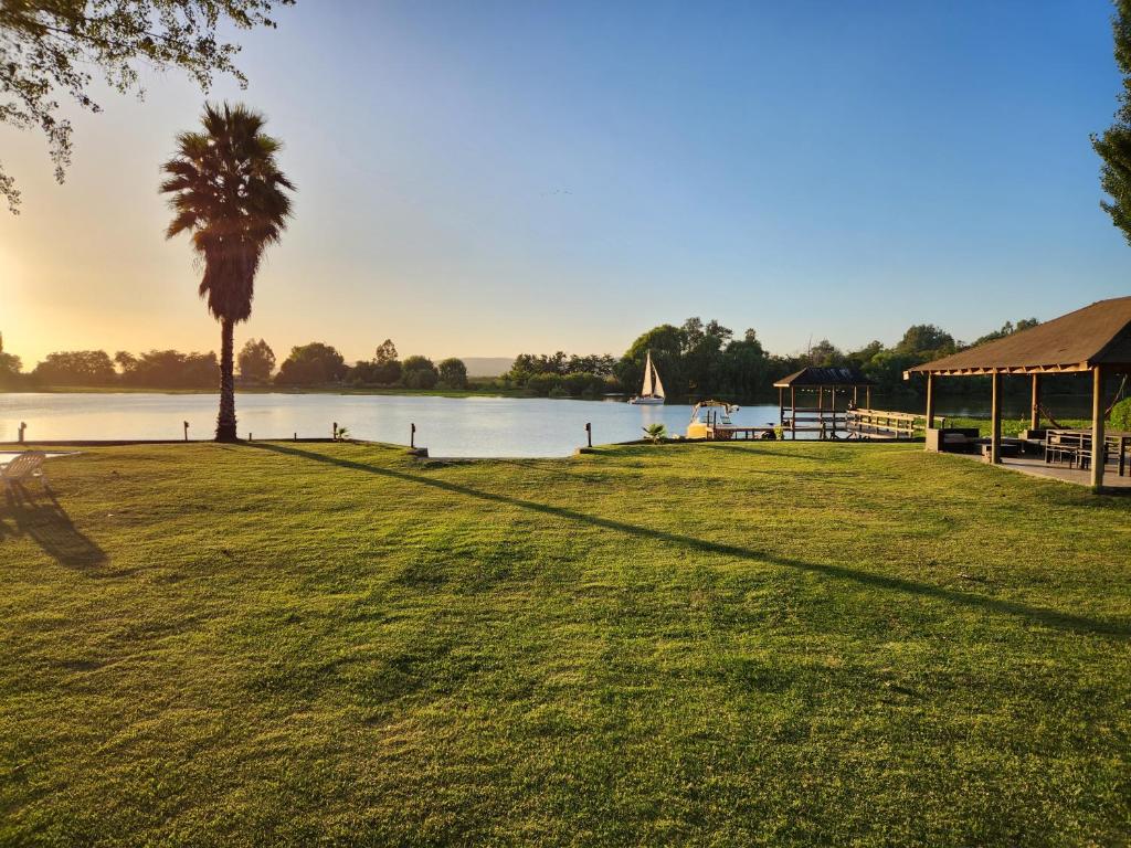 een grasveld met een palmboom en een meer bij Casa en lago rapel con orilla propia in El Durazno