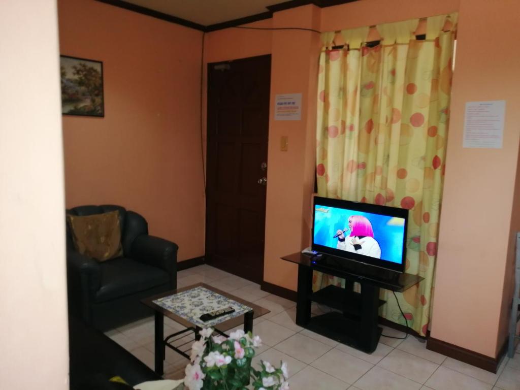 a living room with a television and a chair at Cranberry's place #3 in Iloilo City