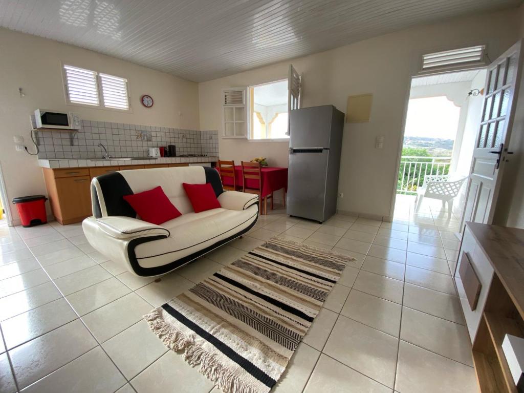 a living room with a white chair and a refrigerator at ALIZÉ CAP in Sainte-Anne