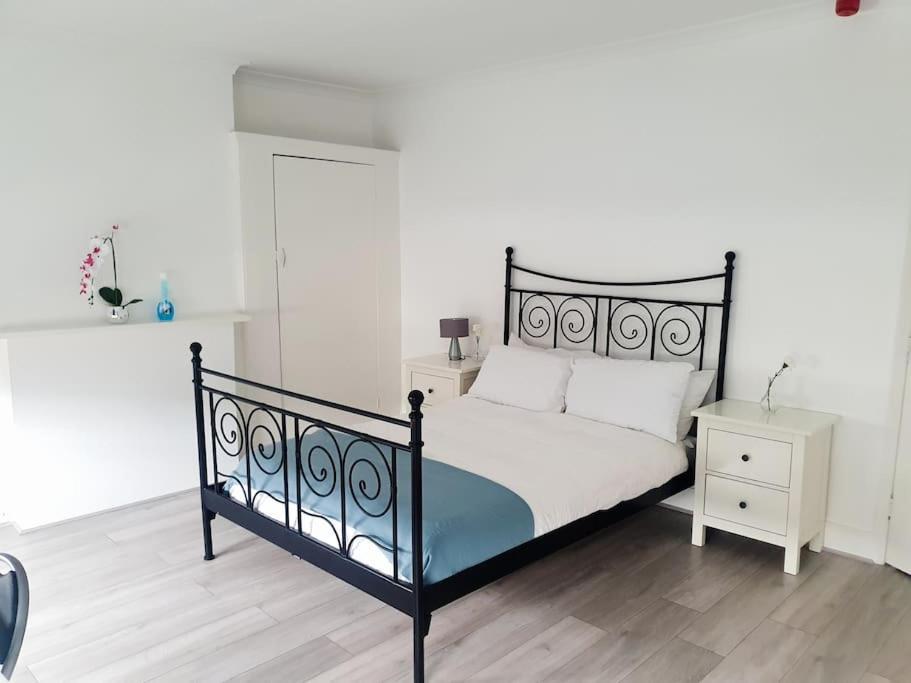 a bedroom with a black and white bed and a night stand at Spacious 5 bedroom House in South Norwood Croydon in Norwood