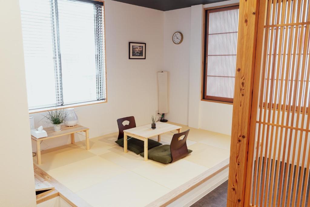a living room with a table and chairs and windows at Spacious One Room Apartment for up to 5ppl w Kitchenette - space kuhonji in Kumamoto