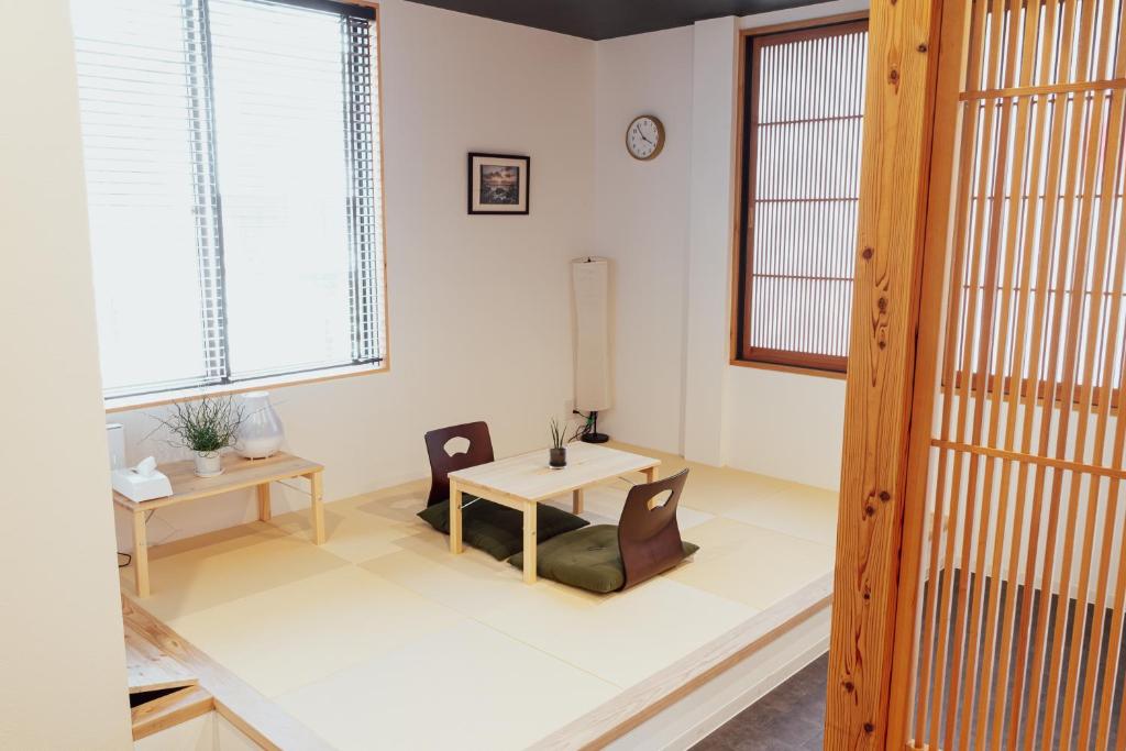 - un salon avec une table, des chaises et des fenêtres dans l'établissement Spacious One Room Apartment for up to 5ppl w Kitchenette, à Kumamoto