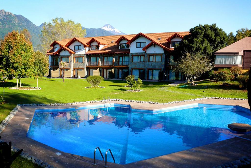 uma casa grande com uma grande piscina em frente em Hotel Pucon Green Park em Pucón