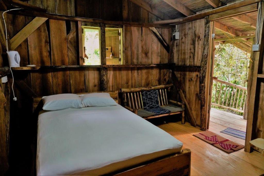 ein Schlafzimmer mit einem Bett in einem Holzzimmer in der Unterkunft Natty Tropical Valley in Roseau