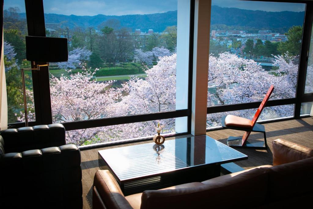 uma sala de estar com vista para as árvores de akura a partir de uma janela em Riverte Kyoto Kamogawa em Quioto