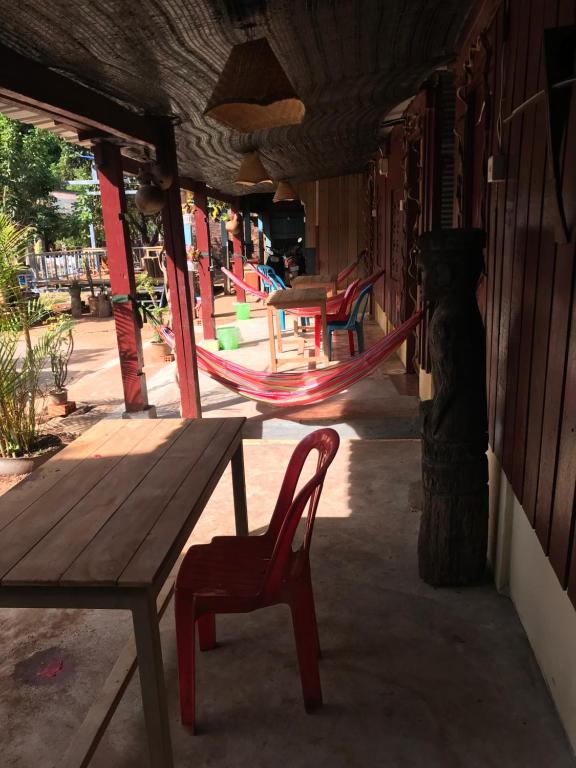 a porch with a wooden table and a bench and swings at Happy Homestay Banlung & Trekking in Banlung