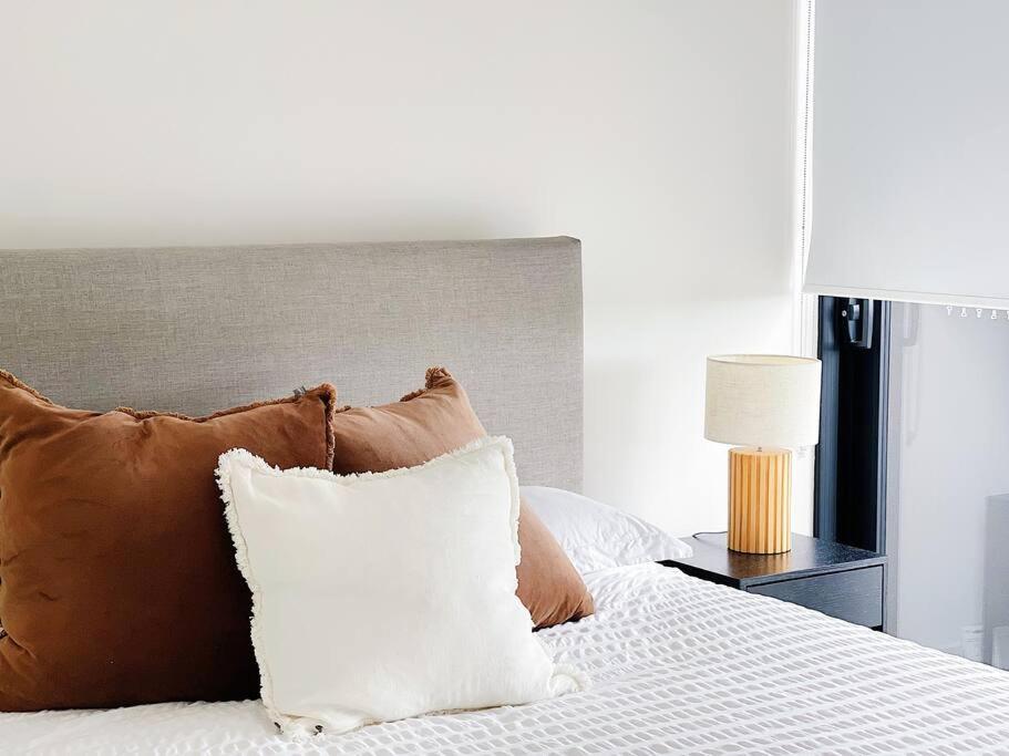 - une chambre avec un lit doté d'oreillers et d'une lampe dans l'établissement Chermside deluxe 3 bedroom brand new apartment, à Brisbane
