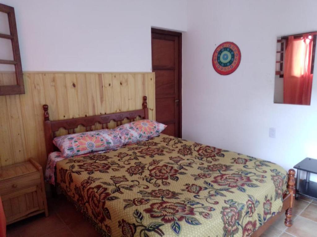 a bedroom with a bed with a floral bedspread at Residencial ANAHATA in Capilla del Monte
