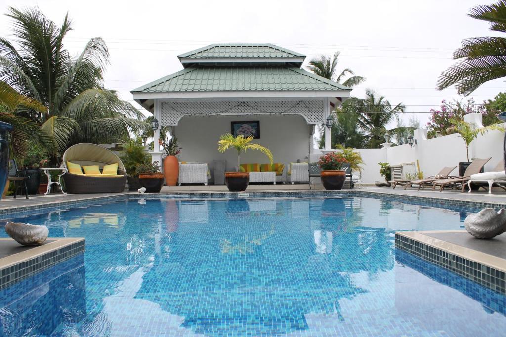 a pool at a resort with chairs and a gazebo at Le Bonheur Villa in Victoria