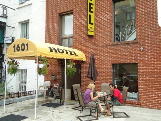 duas pessoas sentadas numa mesa debaixo de um guarda-chuva em Hotel Bon Accueil em Montréal