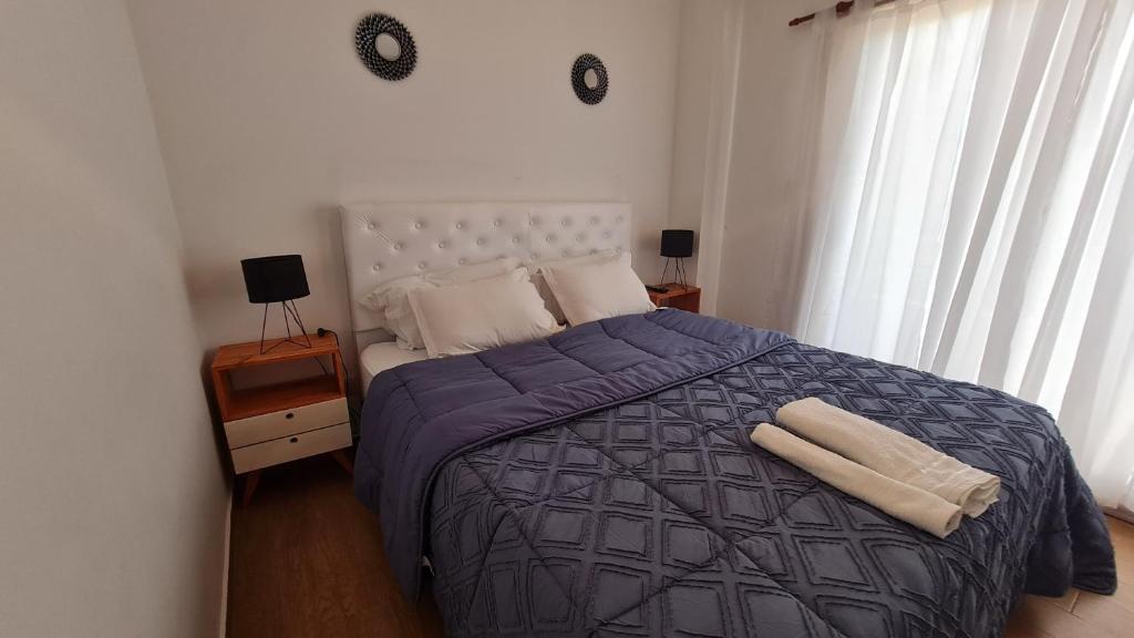 1 dormitorio con 1 cama con edredón y almohadas azules en Precioso departamento en zona gastronomica con cochera en Lanús