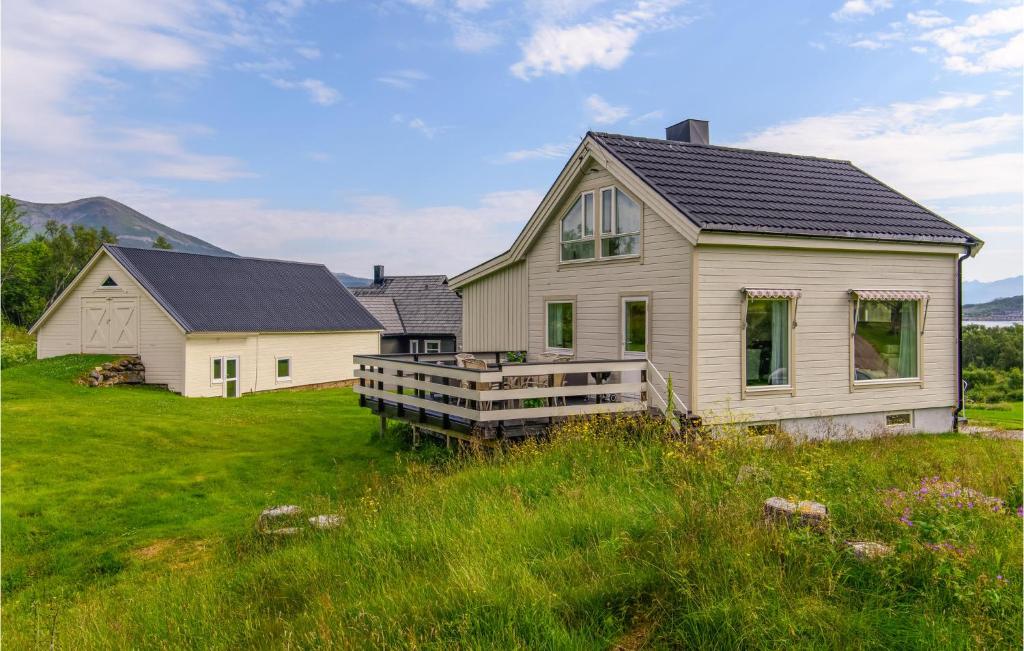 une maison blanche avec une terrasse couverte dans un champ dans l'établissement Beautiful Home In Stokmarknes With House A Panoramic View, à Stokmarknes