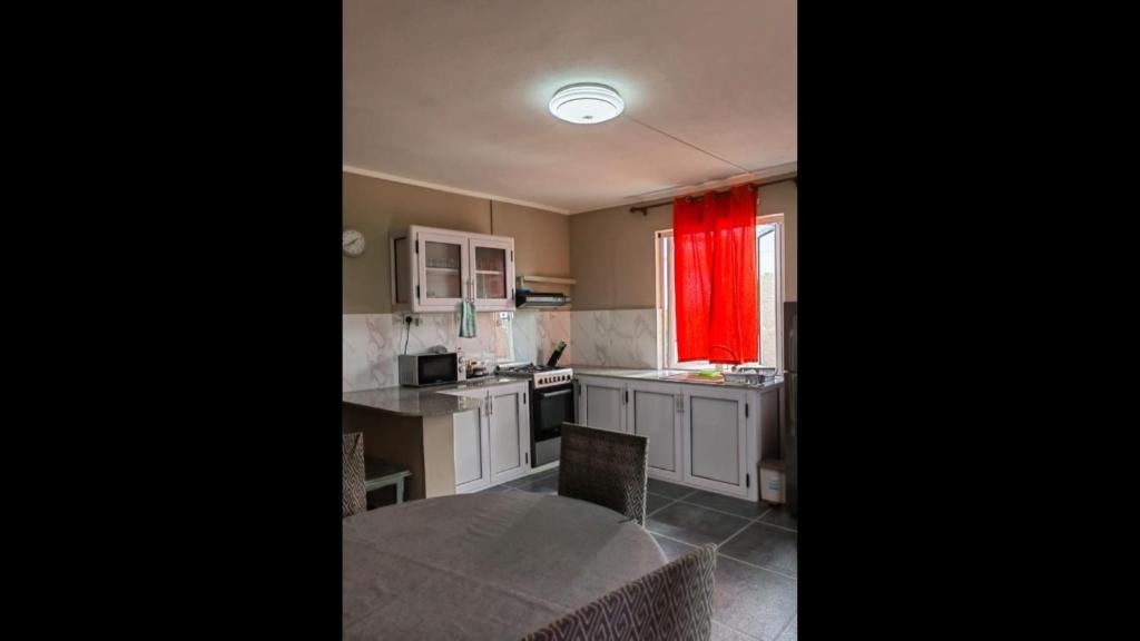 a kitchen with a table and a red curtain at Residence Devika2 Trou aux Biches in Trou aux Biches