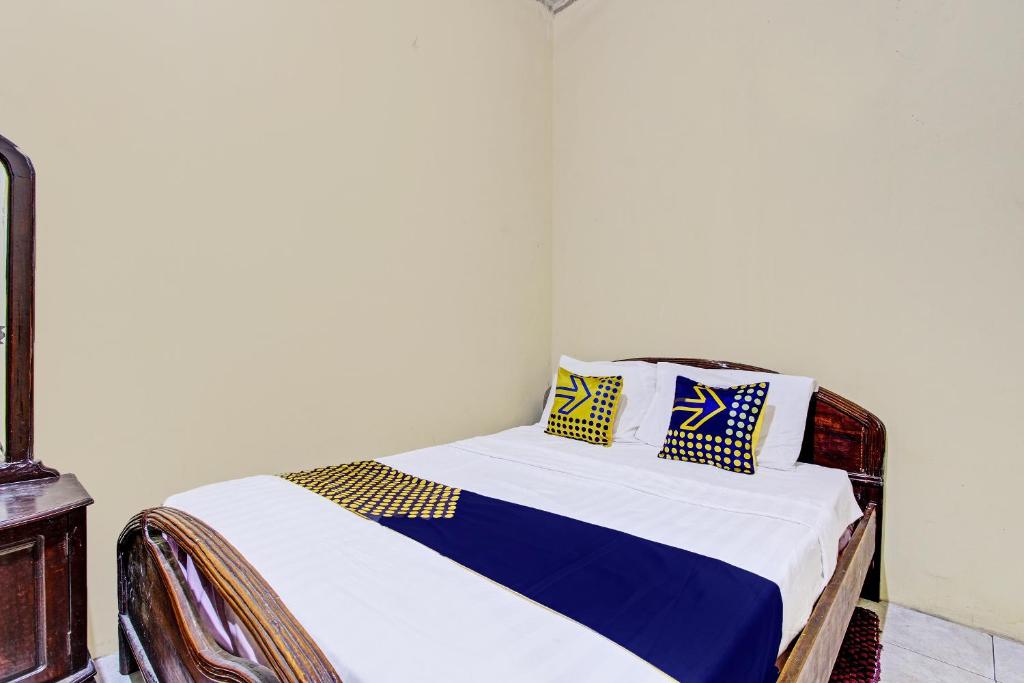 1 dormitorio con 1 cama con almohadas azules y amarillas en SPOT ON 92188 Ndalem Eyang Guesthouse Syariah, en Demak