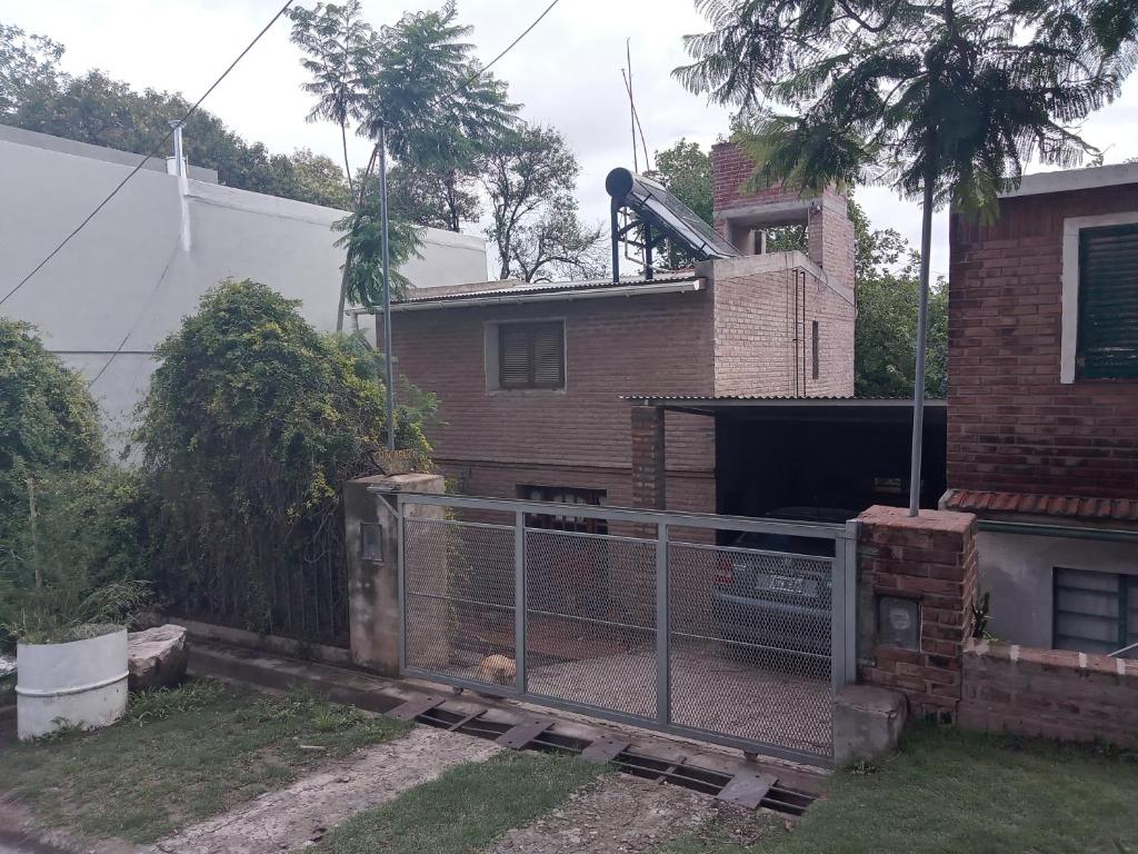 una cerca frente a una casa con un perro en Los colibries en Salsipuedes