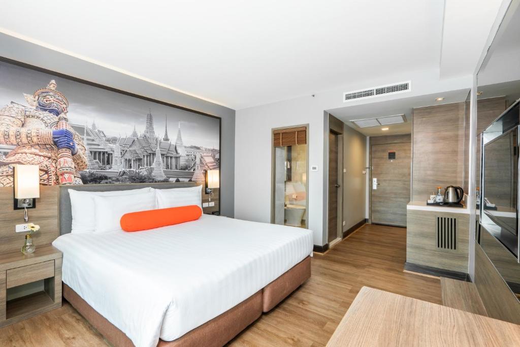 Citrus Sukhumvit 11 by Compass Hospitality في بانكوك: غرفة نوم بسرير كبير ولوحة على الحائط