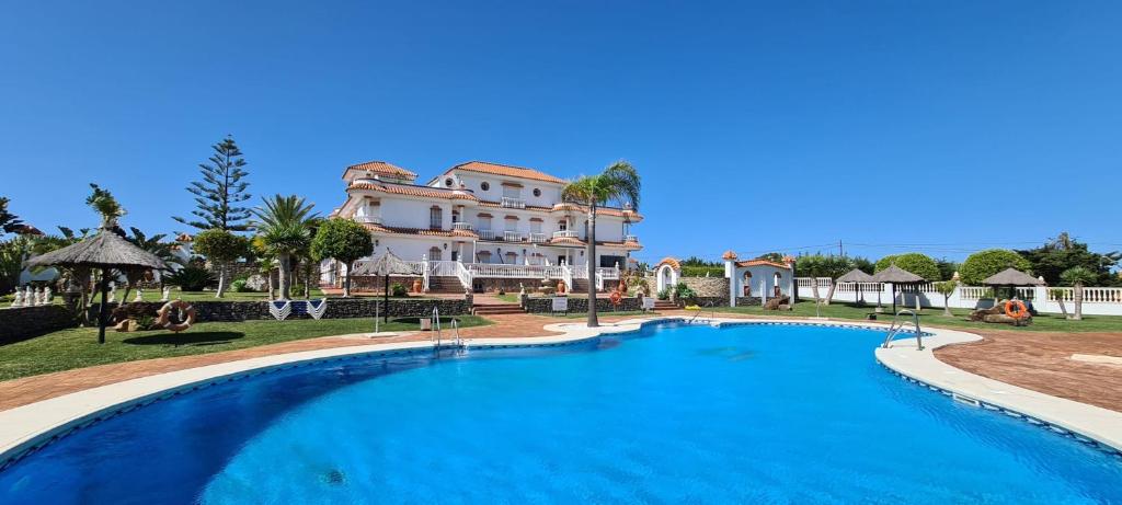 una gran piscina frente a una casa grande en Hotel Diufain, en Conil de la Frontera