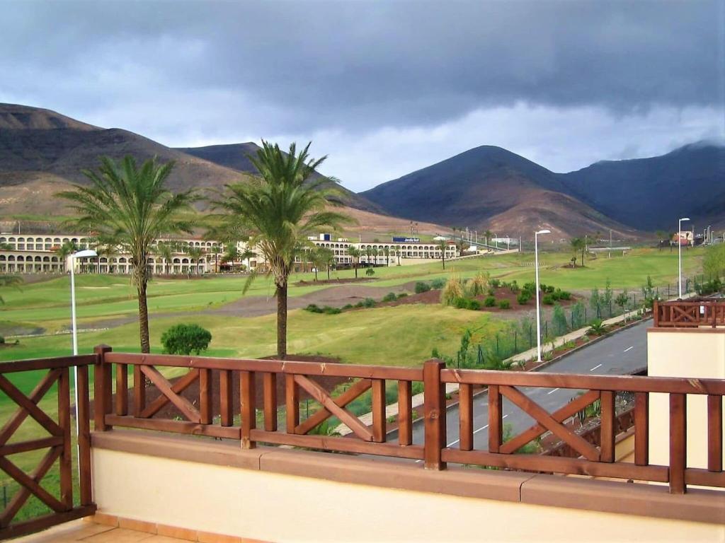 a balcony with a view of a golf course and mountains at Belvilla by OYO Holiday home in Jand a in Morro del Jable