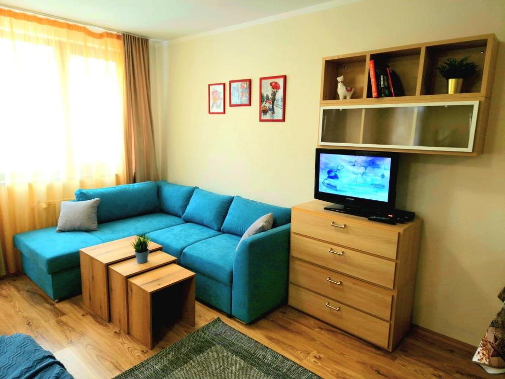a living room with a blue couch and a tv at Студио D-41 в Апарт-хотел Боровец Гардънс in Borovets