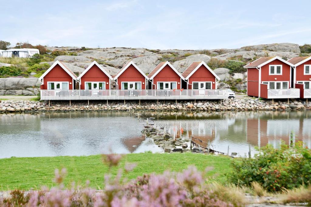 uma fila de casas vermelhas ao lado de uma massa de água em First Camp Solvik-Kungshamn em Väjern