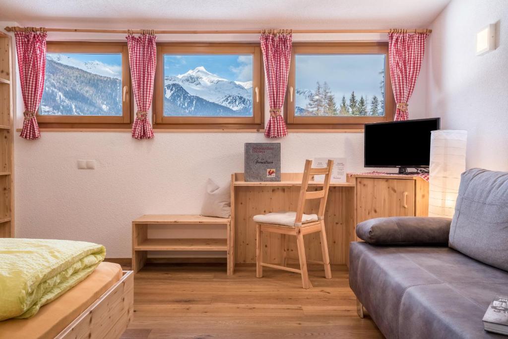 een woonkamer met een bank en een bureau met een computer bij Mountainfarm Innertrein Jöchl in Cadipietra
