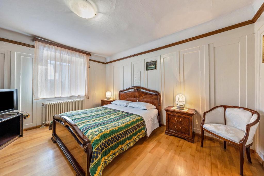 Appartamento Pisani في Brez: غرفة نوم بسرير وكرسي وتلفزيون