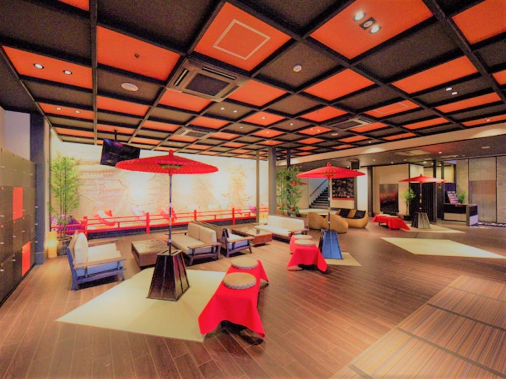 una hall con tavoli, sedie e ombrelloni rossi di LiVEMAX RESORT Aki Miyajima a Miyajima