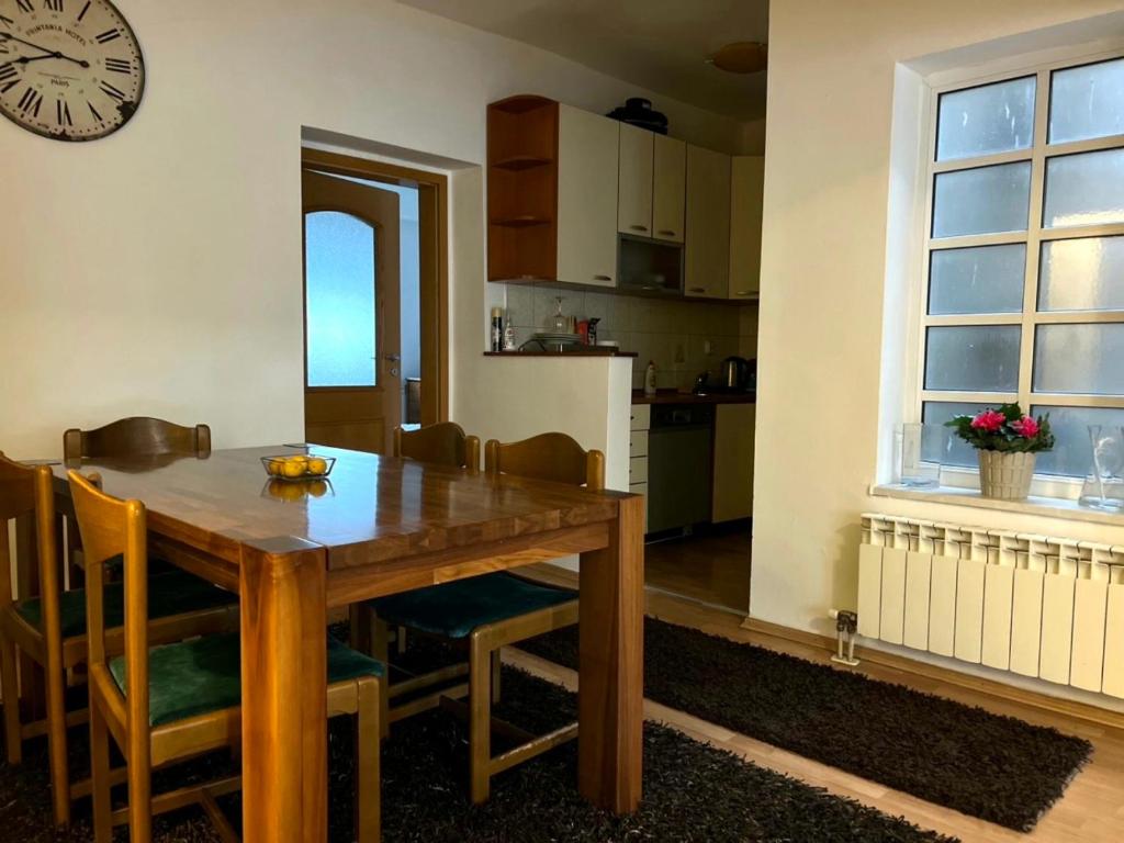 uma cozinha e sala de jantar com uma mesa de madeira e um relógio em Homy apartment in city center Marijin Dvor em Sarajevo