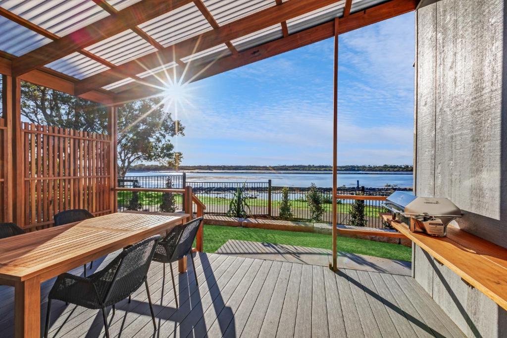 una terraza con mesa y sillas y vistas al agua en Reflections Urunga - Holiday Park, en Urunga