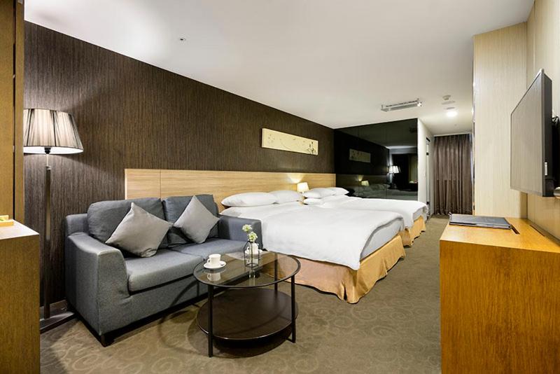 Habitación de hotel con cama y sofá en Beacon Hotel, en Taichung