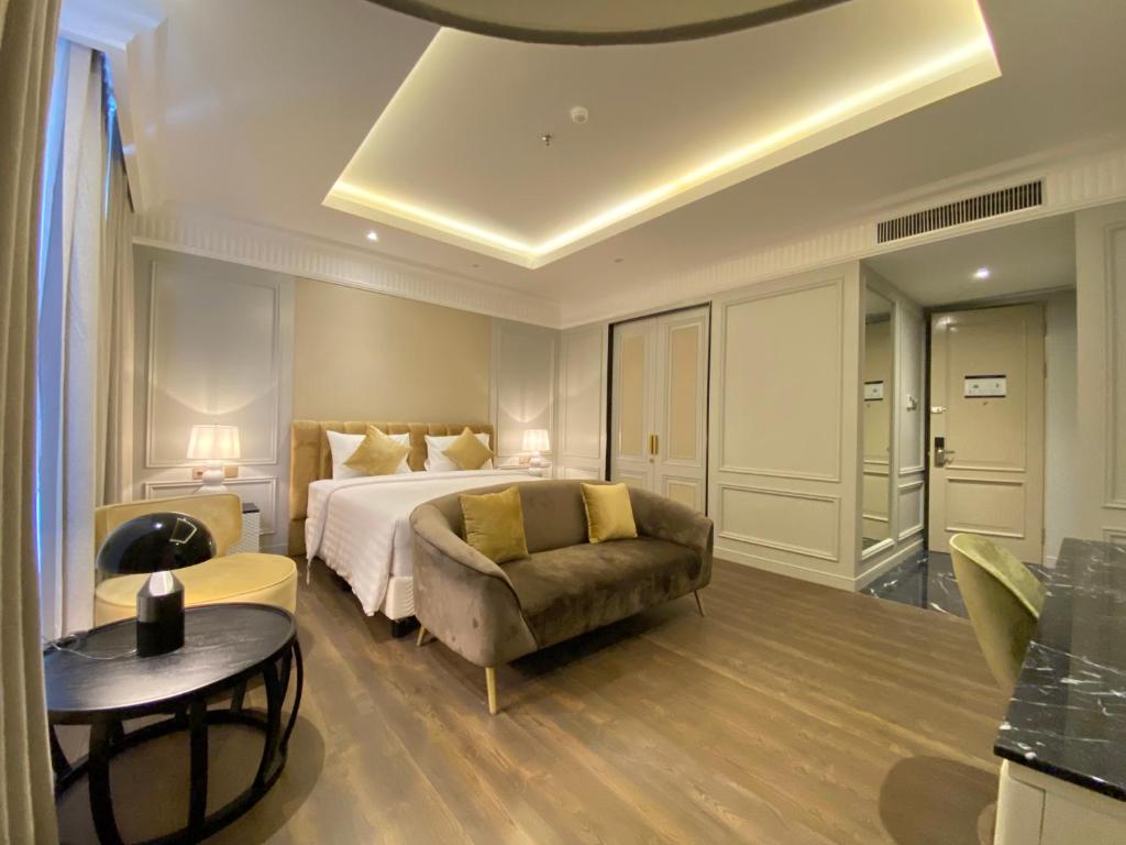 Maia Hotel Jakarta في جاكرتا: غرفة نوم بسرير واريكة وطاولة