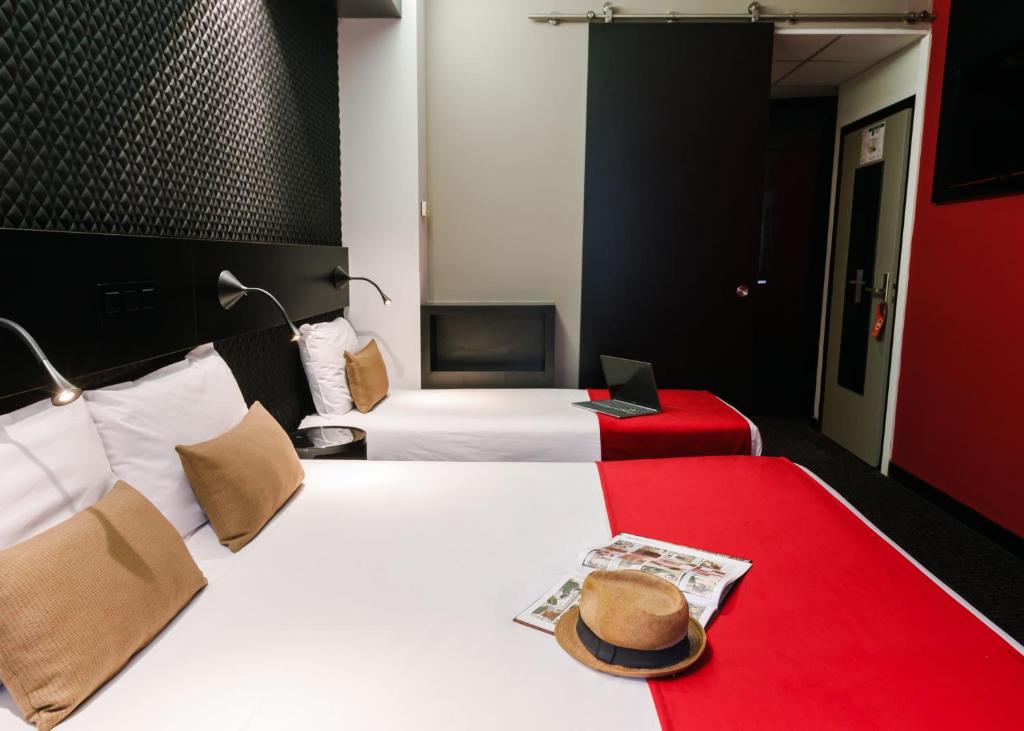 a hotel room with two beds with a hat on the bed at Hôtel de Noailles in Lyon