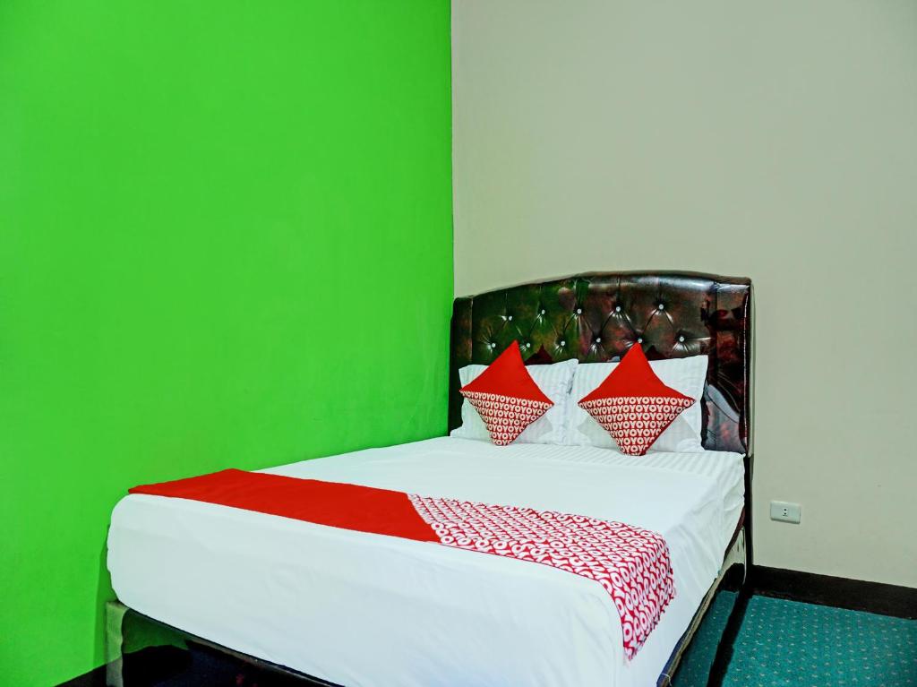 um quarto verde com uma cama com almofadas vermelhas e brancas em OYO 92189 Wisma Inayah Syariah em Palimbão