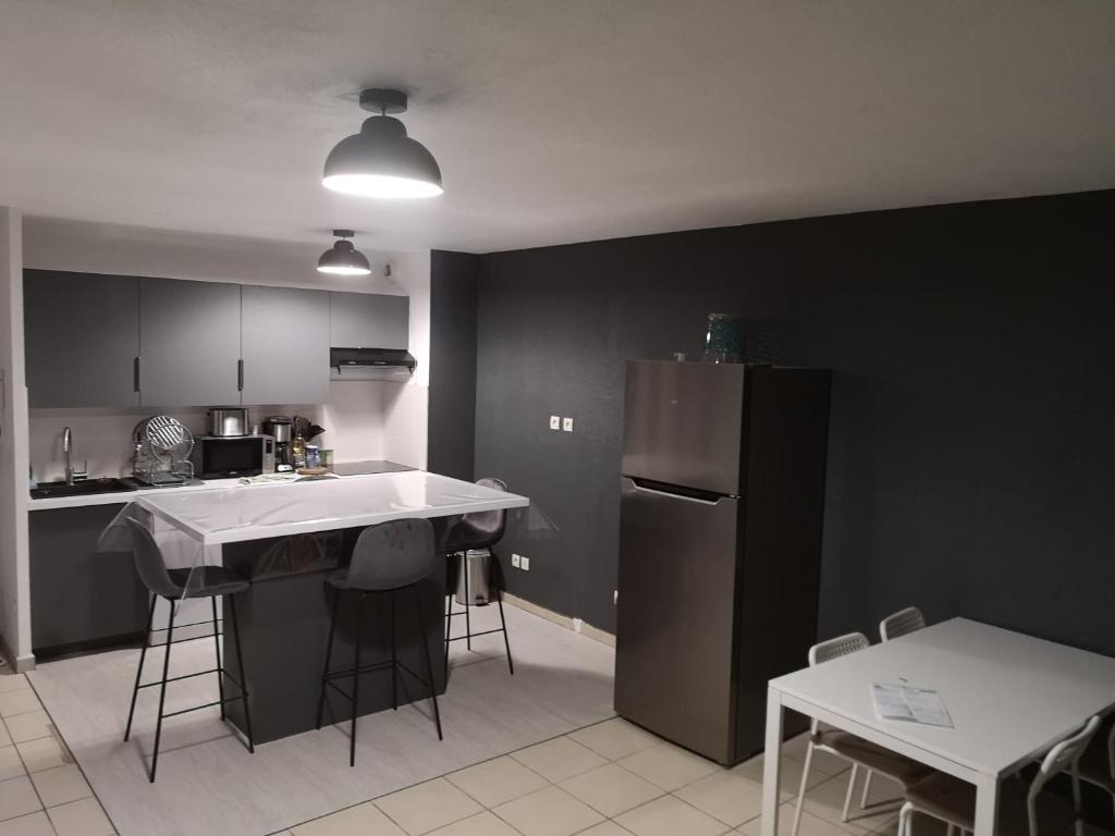 une cuisine avec des armoires noires et un comptoir blanc dans l'établissement Au cœur du village d' Argelès-sur-Mer, à Argelès-sur-Mer