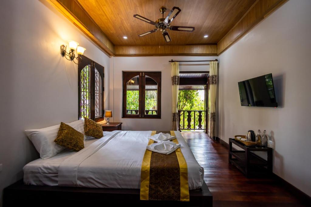 um quarto com uma cama e uma ventoinha de tecto em Villa Mira Heritage em Luang Prabang