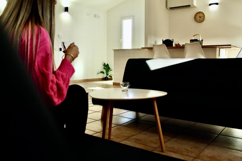 una mujer sentada en una silla con una mesa en B-Guest House, en Oristano