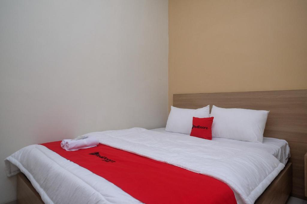 a bed with a red and white blanket on it at RedDoorz Plus near UMS Solo 2 in Solo