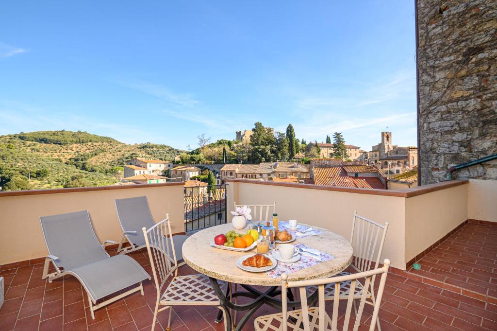 un tavolo con sedie su un balcone con tavolo e frutta di Il Chiostro Appartamenti & Suites a Suvereto