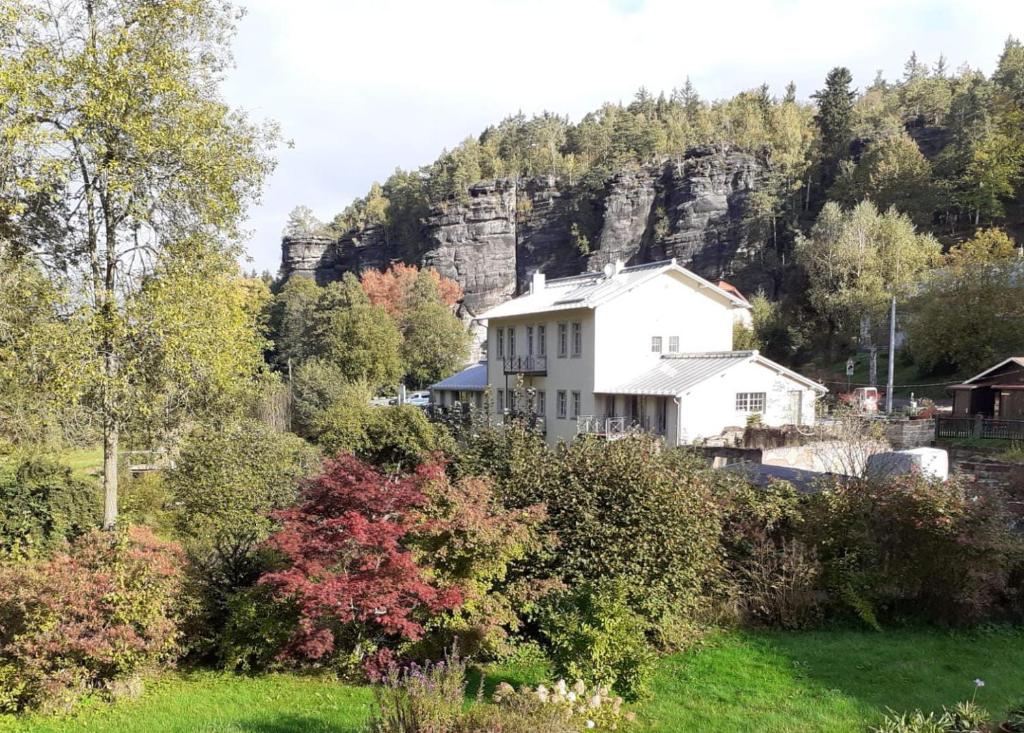 a white house in front of a mountain at Ferienwohnung Parkblick im Badehaus in Schweizermühle