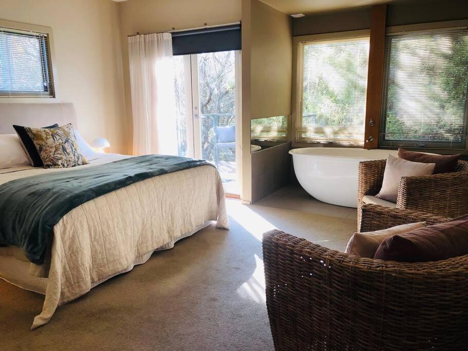 um quarto com uma cama, uma banheira e uma cadeira em Hepburn hideaway studio em Hepburn Springs