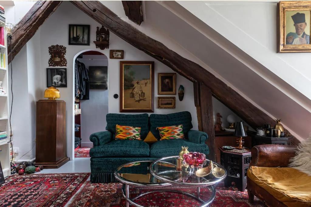 uma sala de estar com um sofá azul e uma mesa de vidro em A writer's flat em Paris