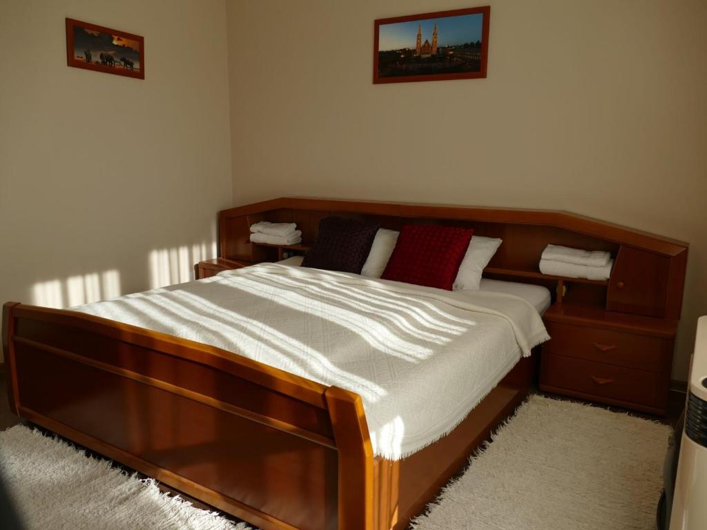 a bedroom with a wooden bed with two red pillows at Sétány apartman in Mórahalom