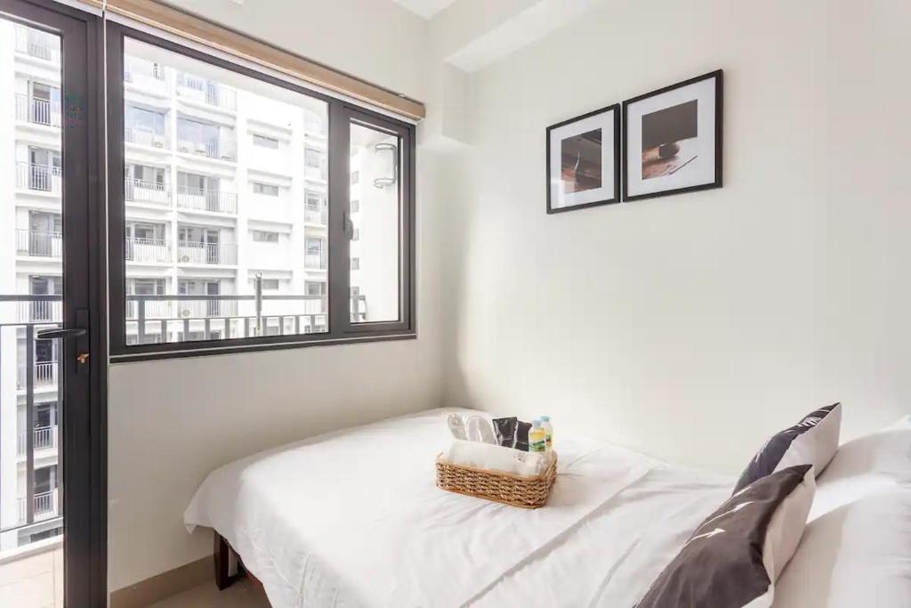 a bedroom with a white bed and a window at Shore 2 Apartment with Balcony in Manila