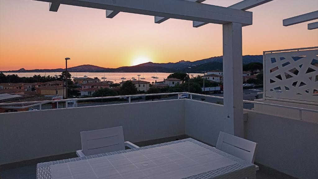 a balcony with a table and two chairs and the sunset at Welcomely - White Terrace - Condominio AcquaLife in Cannigione