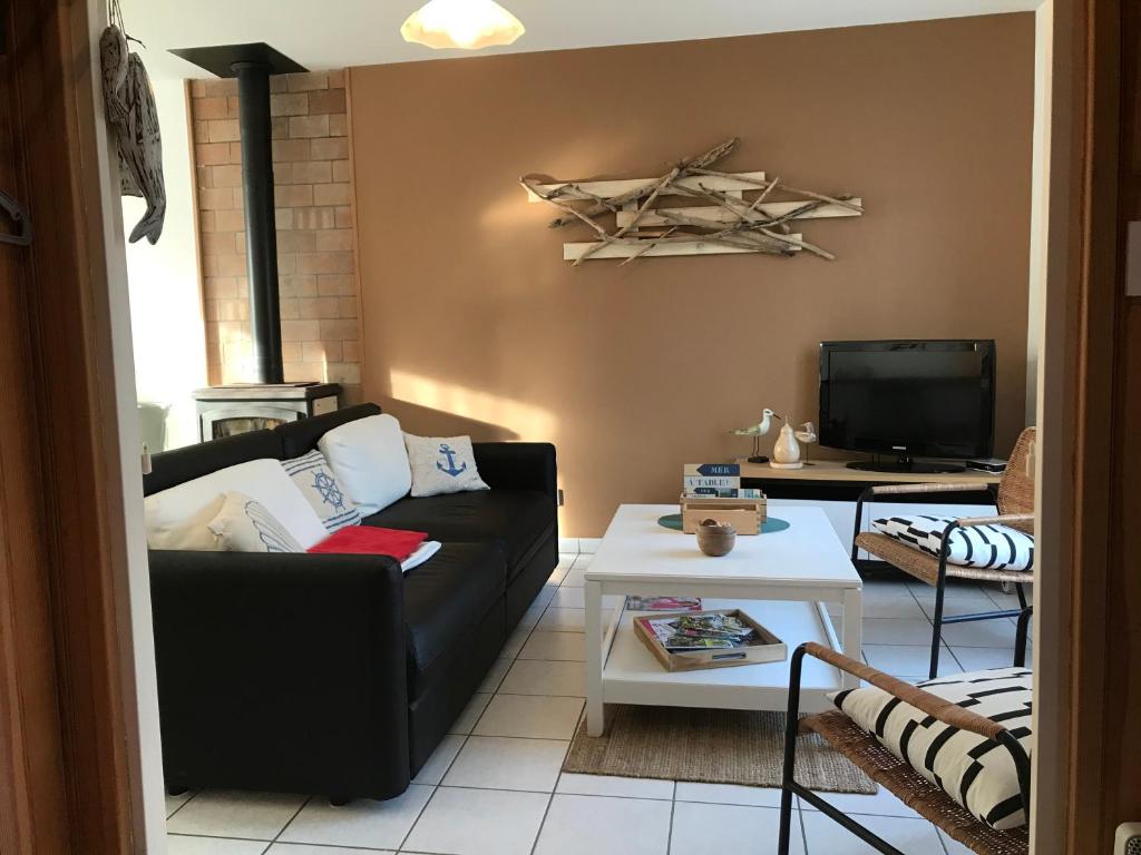 ein Wohnzimmer mit einem schwarzen Sofa und einem TV in der Unterkunft Maison avec jardin, à 600m de la mer à TREGASTEL Réf - 57 in Trégastel